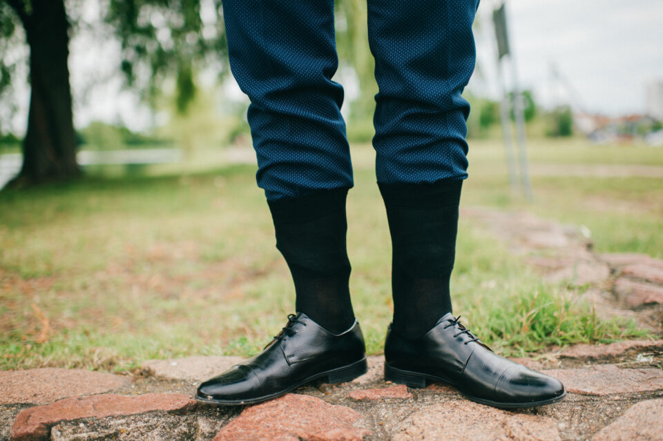 Unrecognizable man in wedding suit standing outdoor with socks put on trousers. Groom in black leather shoes standing on nature at stone. Freaky, foolish, absurd, odd clothes style. Funny marriage day Ingenia Asignatura de Industriales UPM